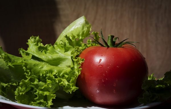 Красный помидор и зеленые листья салата